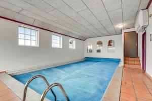 an indoor swimming pool with blue water in a room at Thatched house with pool by the sea - SJ690 in Harboør