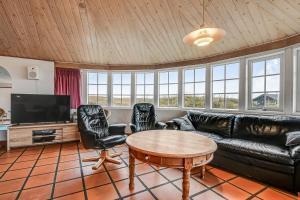 a living room with a leather couch and a table at Thatched house with pool by the sea - SJ690 in Harboør