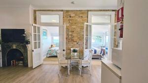 comedor con mesa de cristal y pared de ladrillo en Direct Beachfront Sunrise Apartment - The Coachhouse, en Narrabeen