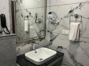 a white bathroom with a sink and a mirror at SABU's GRAND ROYALE HOTEL in Trivandrum