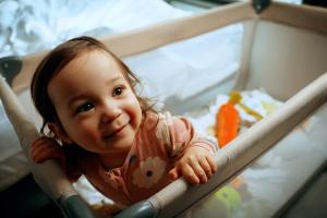 a little girl is sitting in a crib at MEININGER Hotel Bordeaux Gare Saint-Jean in Bordeaux