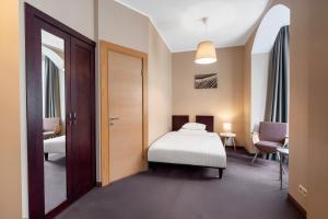 a bedroom with a bed and a door and a chair at RIJA Riga City Centre Hotel in Rīga +37 photos