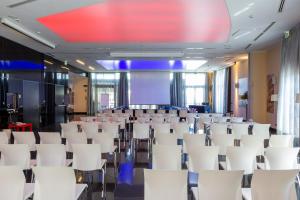 a conference room with white chairs and a projection screen at Amatì Design Hotel in Zola Predosa +157 photos