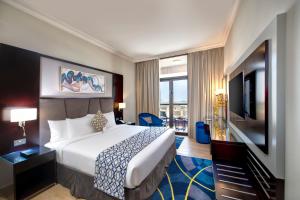 a hotel room with a bed and a flat screen tv at Two Seasons Hotel & Apartments in Dubai +98 photos