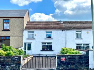 ein weißes Haus mit einem Tor davor in der Unterkunft Miners cottage(1840)Nr. Brecon,Tower Zip & Bike Pk in Aberdare