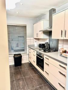 eine Küche mit weißen Schränken und einem Herd mit Backofen in der Unterkunft 5 Bedroom Contractors Accommodation in Dartford Kent - Spacious Holiday Home - Close To Dartford Crossing - Close To City Centre in Dartford