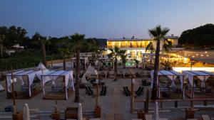 a resort with a lot of tables and palm trees at Linari Sea & Suites in Ormos Panagias