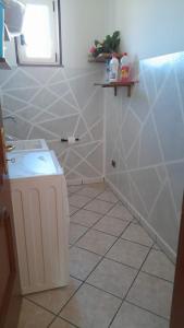 a white tiled bathroom with a toilet and a sink at Finestra su Velia in Marina di Ascea