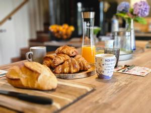 a table with bread and a plate of croissants and orange juice at Chez Sam et Brice in Saint-Georges-Buttavent