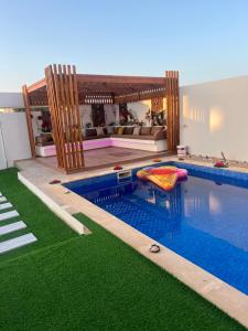 a house with a swimming pool with green grass at Villa vacances proximité plage in Taguermess