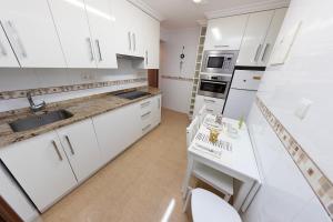 a white kitchen with white cabinets and a sink at Apartamento El Cachupín in Laredo