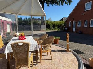 a table with chairs and an umbrella on a patio at Ferienwohnung Bettina 95171 in Rhauderfehn