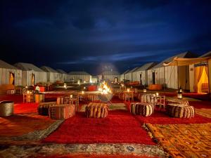 a group of tables and chairs in a field at night at lina safari luxury camp in Merzouga