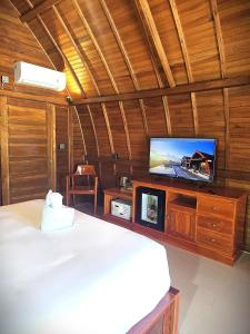 ein Schlafzimmer mit einem Bett und einem Flachbildfernseher in der Unterkunft Dudu Cottage Nusa Penida in Nusa Penida