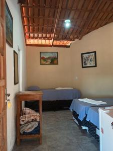 a room with two beds and a table in it at Casa Estrela Matutina Rural in Pirenópolis