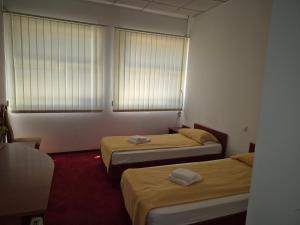 a room with two beds and two windows at Pensiunea MERCUR in Cluj-Napoca
