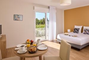 a hotel room with a bed and a table with a dining room at Quality Suites Saint-Paul-l s-Dax in Saint-Paul-lès-Dax