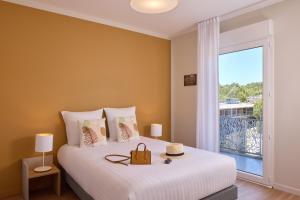 a bedroom with a bed with a large window at Quality Suites Saint-Paul-lès-Dax in Saint-Paul-lès-Dax