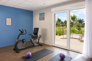 ein Fitnessraum mit Trainingsgeräten und einer Glasschiebetür in der Unterkunft Quality Suites Saint-Paul-l s-Dax in Saint-Paul-lès-Dax + 12 Fotos