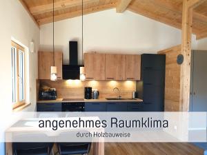 a kitchen with a black refrigerator and wooden cabinets at Ferienhaus Inntal - Ferienwohnung Naunspitz - ruhig schlafen, zentral starten, beliebt bei Wanderern in Kiefersfelden