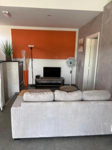 a living room with a white couch and an orange wall at Résidence Basilic in Grâce-Hollogne