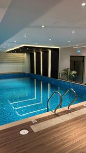 a large swimming pool in a hotel with blue water at Serene 1BHK Central Gulberg Self check-in WiFi Pool in Lahore