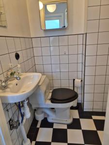 a bathroom with a sink and a toilet with a black seat at Lilla Kari in Varberg +2 photos