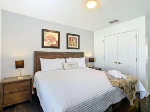 ein Schlafzimmer mit einem großen weißen Bett mit zwei Nachttischen in der Unterkunft Lovely 3BR Villa - Bella Vida Resort - Pool & BBQ! in Kissimmee