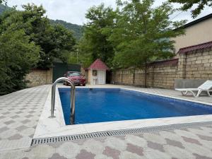 a swimming pool in front of a house with a car at Qabala in Mekhrably