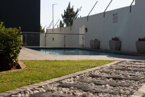 a swimming pool with a stone walkway next to a building at Oasis Comfort Apartment in Midrand