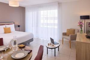 a hotel room with a bed and a table and chairs at Zenitude Hôtel-Résidences Perpignan in Perpignan