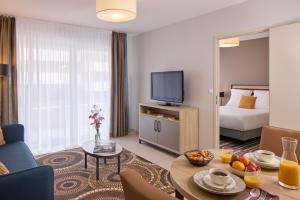 佩皮尼昂Zenitude Hôtel-Résidences Perpignan的一间带床和客厅的酒店房间