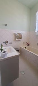 a white bathroom with a sink and a bath tub at Casa 420 in Diamantina