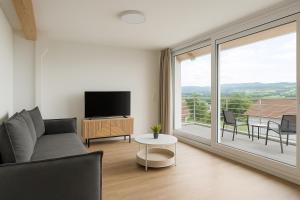 a living room with a couch and a large window at SMS-Homes I Auszeit am See #2 in Waltenhofen