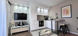 a living room with a kitchen with a tv on a wall at Apartman Renata in Županja
