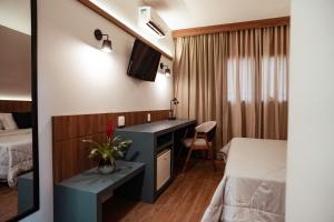 a small hotel room with a desk and a bed at Matiz Jaguariúna in Jaguariúna
