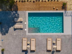 einen Blick über einen Pool mit Chaiselongues in der Unterkunft Olive Βay Villa in Tragaki