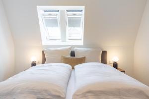a bedroom with two beds with white sheets and a window at Villa Dornkamp 5 - Luxuriöse Ferienwohnung für 2 Personen inklusive Sauna und Balkon in Timmendorfer Strand