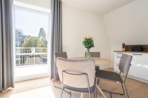 a dining room with a table and chairs and a large window at Villa Dornkamp 5 - Luxuriöse Ferienwohnung für 2 Personen inklusive Sauna und Balkon in Timmendorfer Strand