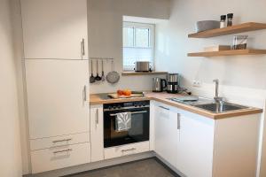 une petite cuisine avec des armoires blanches et un évier dans l'établissement Ferienwohnung in der alten Scheune Wiesenblick für 3 Personen, à Ohne
