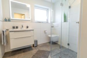 a white bathroom with a sink and a toilet at Dorumer Sielhuus 4 - Ferienwohnung mit Garten und Sauna in Dorum +24 photos