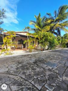 a resort with palm trees and a stone driveway at Country Club Pititinga in Pititinga