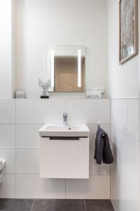 a white bathroom with a sink and a mirror at Ferienhaus Sonnenweg 32 - Sauna, Garten und Seeblick inklusive in Diemelsee