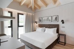 a bedroom with a large white bed and a desk at Lago Dorato Marina Lodge - Lakefront in Colico
