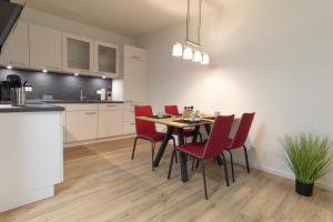 a kitchen and dining room with a table and red chairs at Herz von Kellenhusen 2 mit Garten und Sauna in Kellenhusen