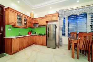 a kitchen with wooden cabinets and a stainless steel refrigerator at Ngoc Trai 01 Villa FLC Sam Son in Sầm Sơn