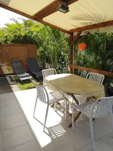 Una mesa y sillas bajo una sombrilla en un patio. en Chez KEKE, en Sainte-Anne