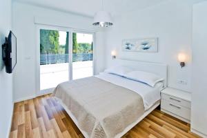 Un dormitorio blanco con una cama y una ventana grande. en Island Hvar Villa LeChalet with Pool, en Bogomolje 57 fotos más