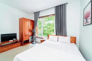 a bedroom with a white bed and a television at Ngoc Trai 02 FLC Sam Son in Sầm Sơn