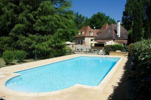 a swimming pool in front of a house at Le Manoir de la Feuillade in Carsac-Aillac